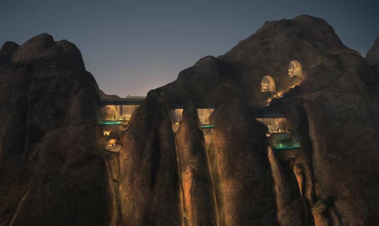 Night view of futuristic architectural project embedded into rocky cliffs in Saudi Arabia.