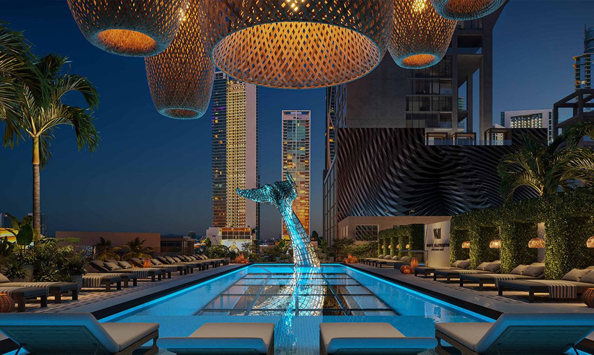 Rooftop pool with elegant lighting and city skyline at night, featuring modern lounge chairs and a striking whale sculpture at West Eleventh Residences, Miami